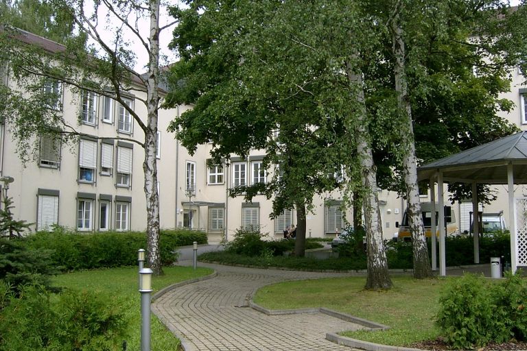 Innenhof mit Wiese und Wegen, im Hintergrund das Gebäude des ASB Wohnzentrums