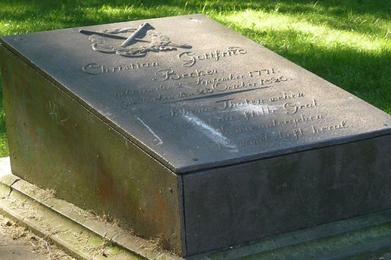 auf einem Steinsockel sind die metallene Grabtafel und Seitenverkleidungen montiert